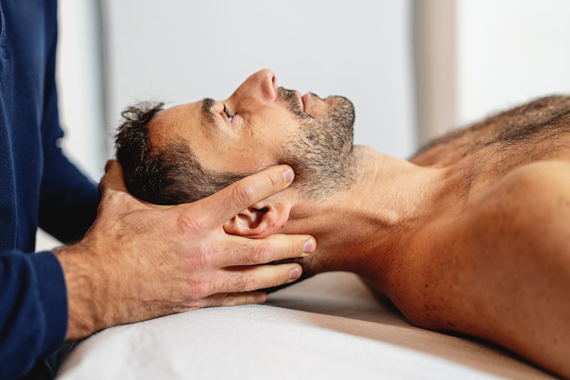 Therapist performing gentle craniosacral therapy on a patient's head and neck